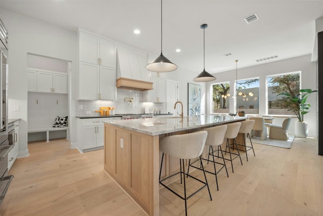 1339 Allen Rd, Austin, TX 78746 - kitchen featuring custom exhaust hood, light wood finished floors, backsplash, a spacious island, and recessed lighting