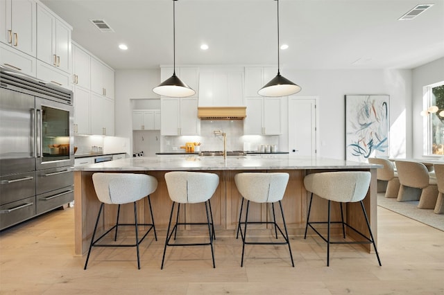 1339 Allen Rd, Austin, TX 78746 - kitchen with stainless steel built in fridge, decorative backsplash, light stone counters, white cabinets, and light wood-style flooring