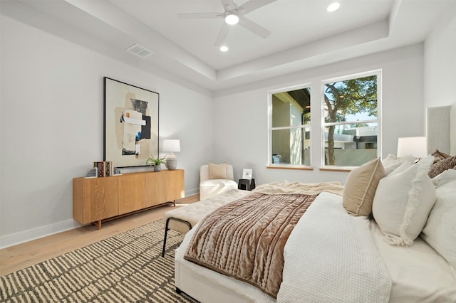 bedroom featuring hardwood / wood-style flooring, ceiling fan, and a tray ceiling