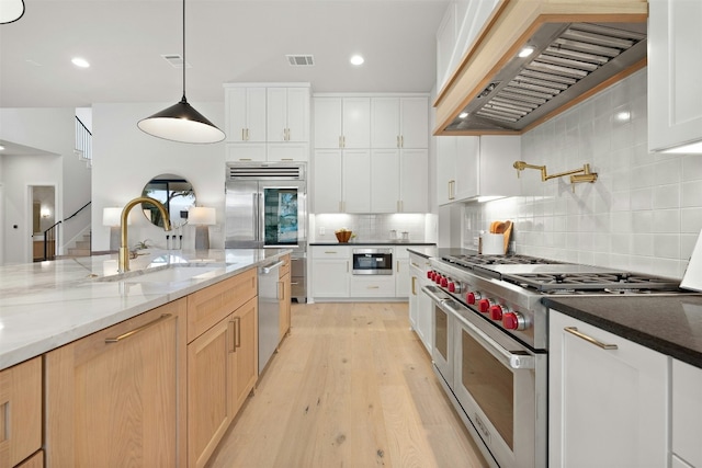 1339 Allen Rd, Austin, TX 78746 - kitchen with high quality appliances, premium range hood, tasteful backsplash, light wood finished floors, and dark stone countertops