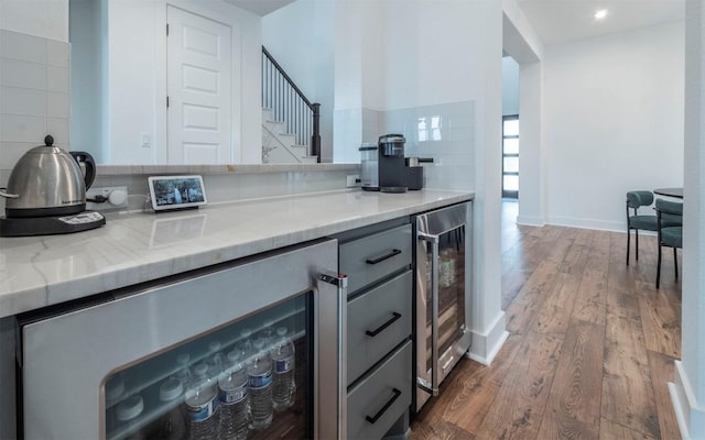 kitchen featuring beverage cooler, light stone counters, backsplash, dark hardwood / wood-style flooring, and gray cabinets