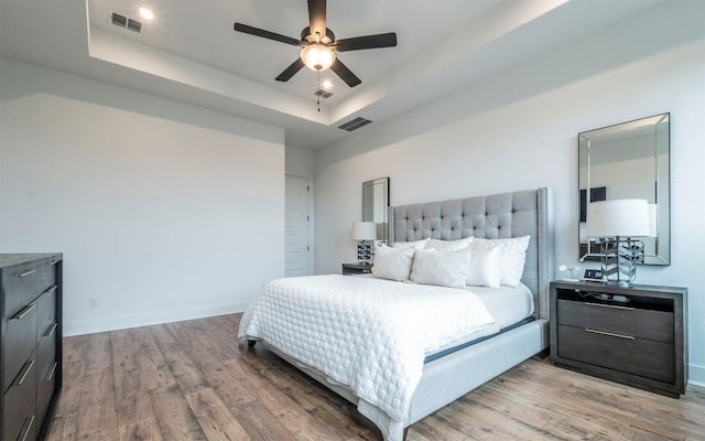 5408 Destination Way, Jonestown, TX 78645 - bedroom with light wood finished floors, a tray ceiling, and a ceiling fan