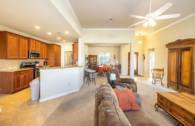 kitchen featuring a peninsula, open floor plan, appliances with stainless steel finishes, decorative backsplash, and brown cabinetry