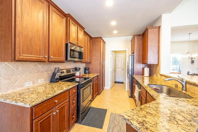 kitchen with light stone counters, decorative light fixtures, an inviting chandelier, appliances with stainless steel finishes, and a sink