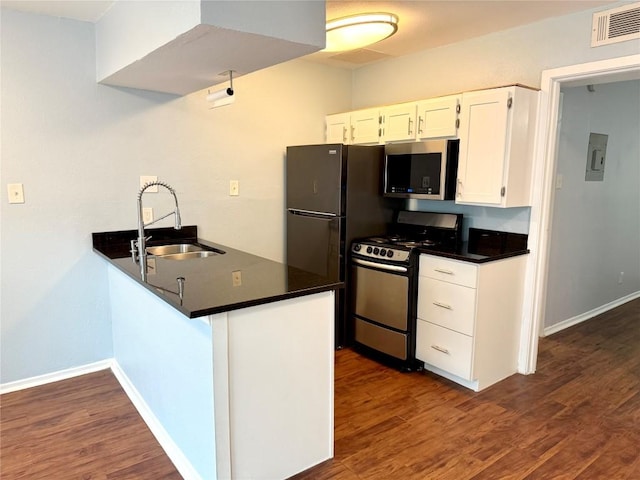 kitchen featuring a sink, visible vents, appliances with stainless steel finishes, dark countertops, and dark wood finished floors