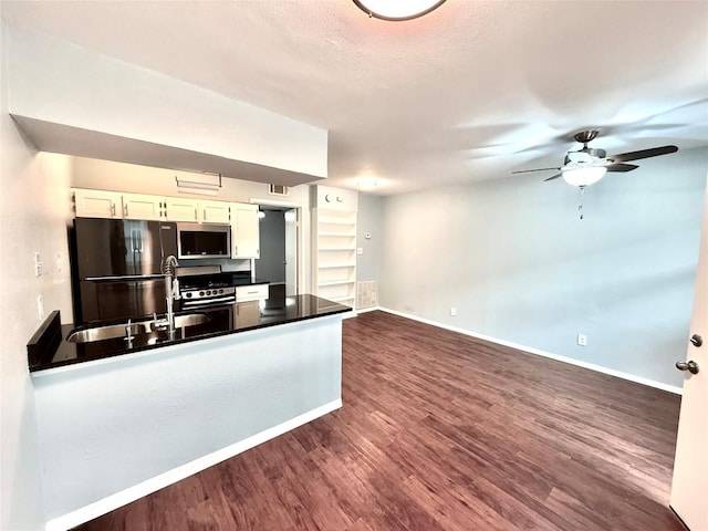 kitchen with stainless steel appliances, white cabinetry, baseboards, dark countertops, and dark wood finished floors