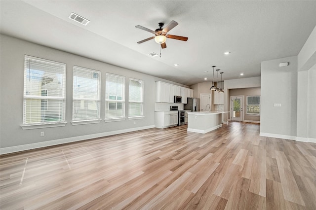 unfurnished living room with light wood-type flooring, lofted ceiling, and ceiling fan