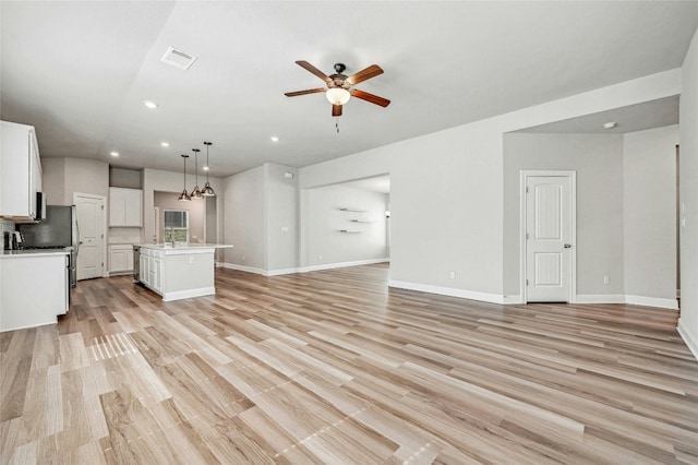 unfurnished living room with ceiling fan, light hardwood / wood-style flooring, and sink