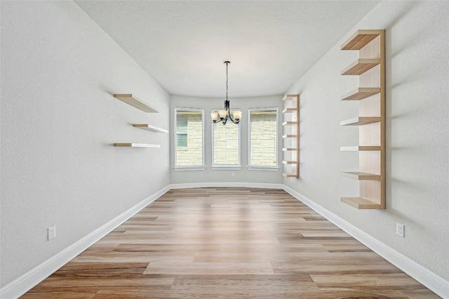 unfurnished dining area featuring light hardwood / wood-style floors and an inviting chandelier