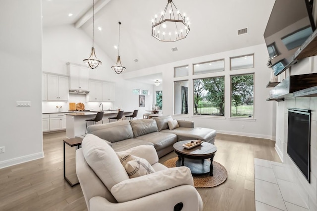 living room with an inviting chandelier, light wood-type flooring, high vaulted ceiling, and beam ceiling