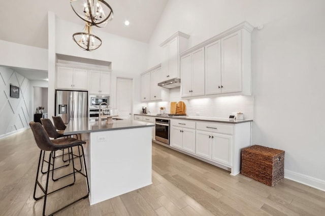 kitchen featuring a center island with sink, stainless steel appliances, white cabinets, light hardwood / wood-style floors, and pendant lighting