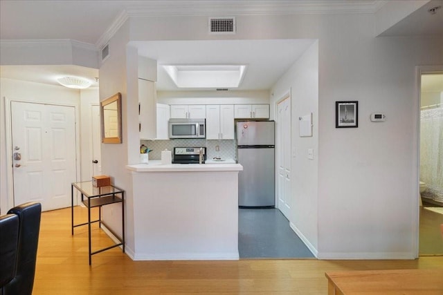 kitchen featuring decorative backsplash, light hardwood / wood-style floors, stainless steel appliances, and white cabinets