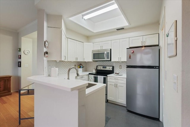 kitchen featuring white cabinetry, kitchen peninsula, stainless steel appliances, backsplash, and a breakfast bar area