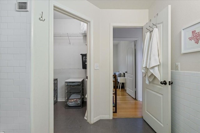 corridor featuring tile walls and dark wood-type flooring