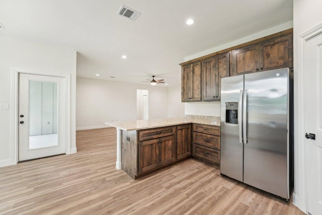 kitchen featuring stainless steel fridge, light wood-style flooring, a peninsula, light stone countertops, and visible vents
