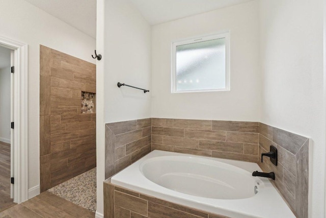 bathroom with a garden tub, wood finished floors, and tiled shower