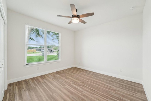 spare room with baseboards, a ceiling fan, and light wood finished floors