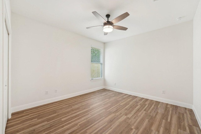 spare room featuring baseboards, wood finished floors, and ceiling fan