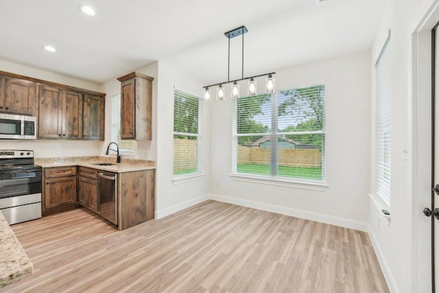 kitchen featuring light wood finished floors, baseboards, a sink, and appliances with stainless steel finishes