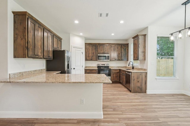 kitchen featuring stainless steel appliances, a peninsula, a sink, visible vents, and light wood-style floors