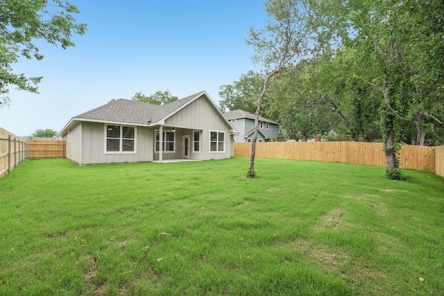 back of house with a fenced backyard and a lawn