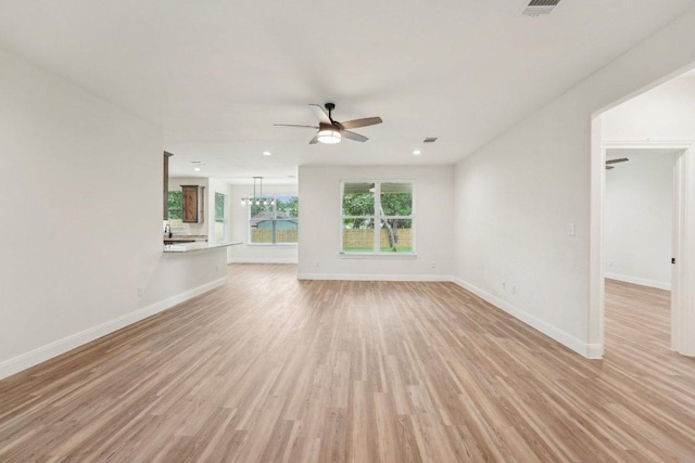 unfurnished living room with light wood-type flooring, baseboards, ceiling fan, and visible vents