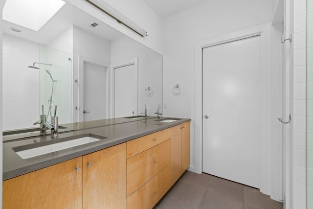 bathroom with tile patterned floors, a skylight, walk in shower, and vanity