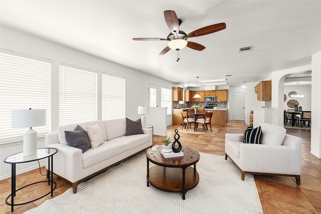 living room featuring ceiling fan with notable chandelier