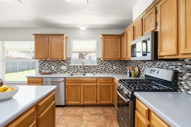 kitchen featuring sink, stainless steel appliances, tasteful backsplash, and a textured ceiling