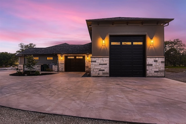 view of front of home featuring stone siding, stucco siding, driveway, and a garage