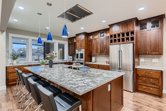 kitchen featuring light stone counters, stainless steel appliances, pendant lighting, and a center island