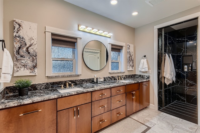 bathroom featuring a tile shower, vanity, and a wealth of natural light