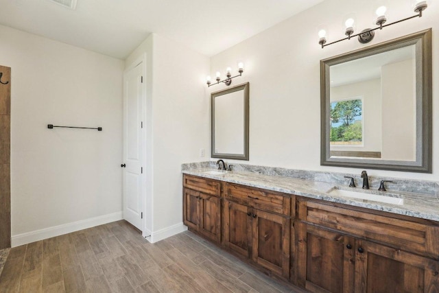 full bathroom featuring wood finished floors, baseboards, a sink, and double vanity