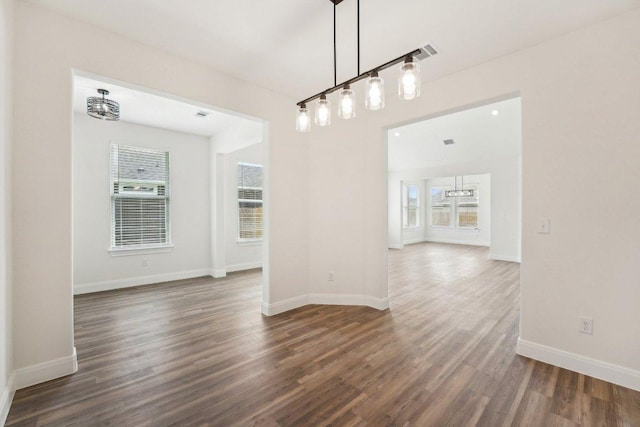 unfurnished dining area with dark wood-type flooring, visible vents, and baseboards