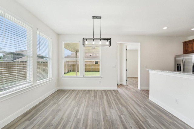 unfurnished dining area featuring recessed lighting, light wood finished floors, and baseboards