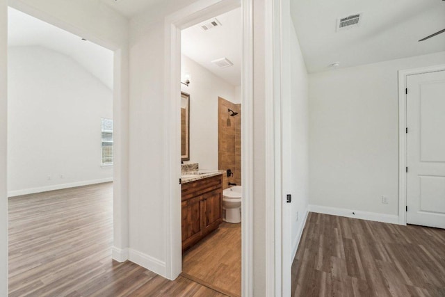 hallway with wood finished floors, visible vents, and baseboards
