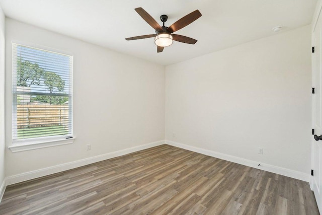 empty room featuring ceiling fan, baseboards, wood finished floors, and plenty of natural light
