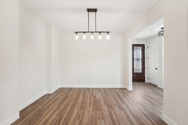 unfurnished dining area featuring wood finished floors and baseboards