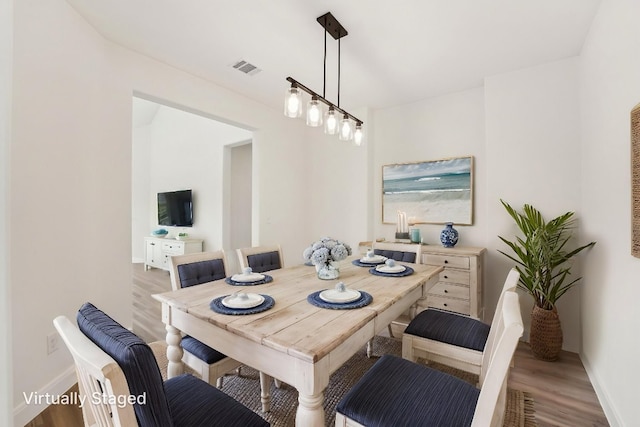 dining space featuring wood finished floors, visible vents, and baseboards