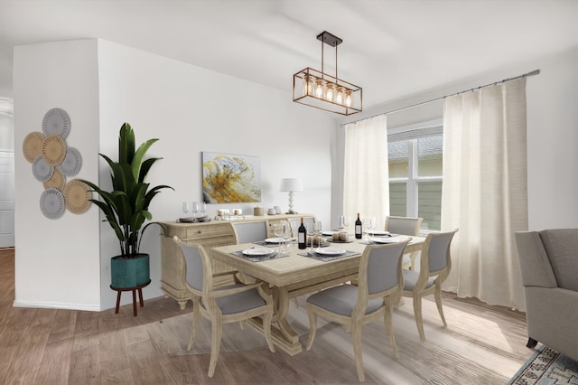 dining space with light hardwood / wood-style floors and a notable chandelier