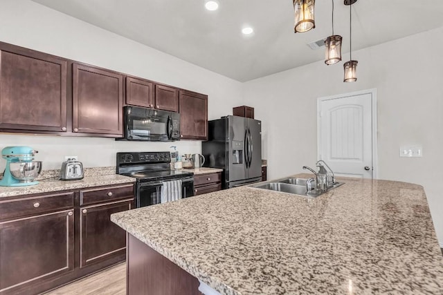 kitchen featuring a center island with sink, sink, pendant lighting, black appliances, and dark brown cabinets