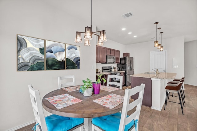 dining space with hardwood / wood-style flooring, sink, and an inviting chandelier