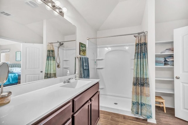 bathroom featuring hardwood / wood-style flooring, lofted ceiling, walk in shower, and vanity