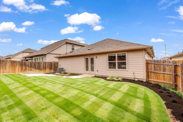 back of property featuring a lawn and central air condition unit