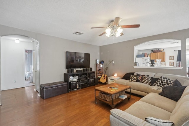 17405 Wiseman Dr, Pflugerville, TX 78660 - living room featuring arched walkways, ceiling fan, wood finished floors, and a textured ceiling