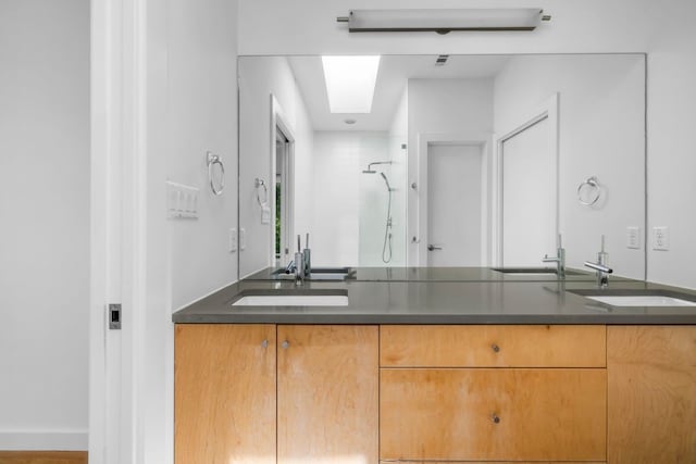 full bath with a skylight, tiled shower, and a sink