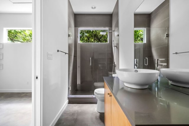 bathroom with toilet, a sink, baseboards, double vanity, and a stall shower