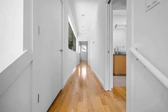 corridor with light wood-style flooring, baseboards, and recessed lighting