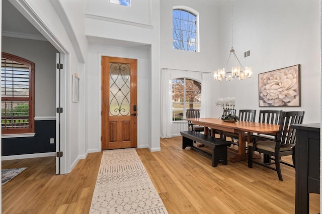 foyer entrance featuring an inviting chandelier, plenty of natural light, and light hardwood / wood-style flooring