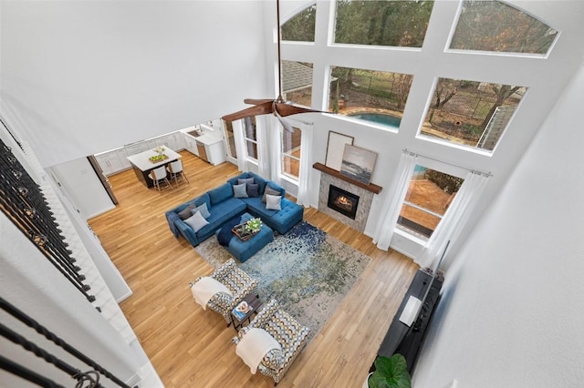 living room featuring hardwood / wood-style flooring, a tile fireplace, and a high ceiling